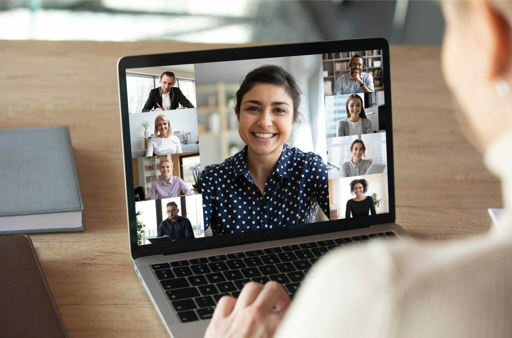 Laptop screen over woman shoulder view, indian businesswoman leading videoconference distant communication group videocall conversation. Diverse friends using modern tech enjoy virtual meeting concept