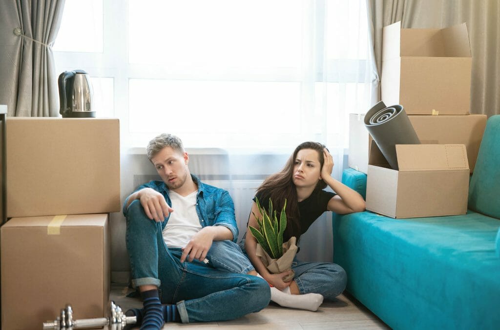 young couple man and woman looking tired sitting on the floor during moving to new appartment unpacking boxes, , moving process
