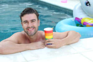 Cute man drinking in rainbow cup.