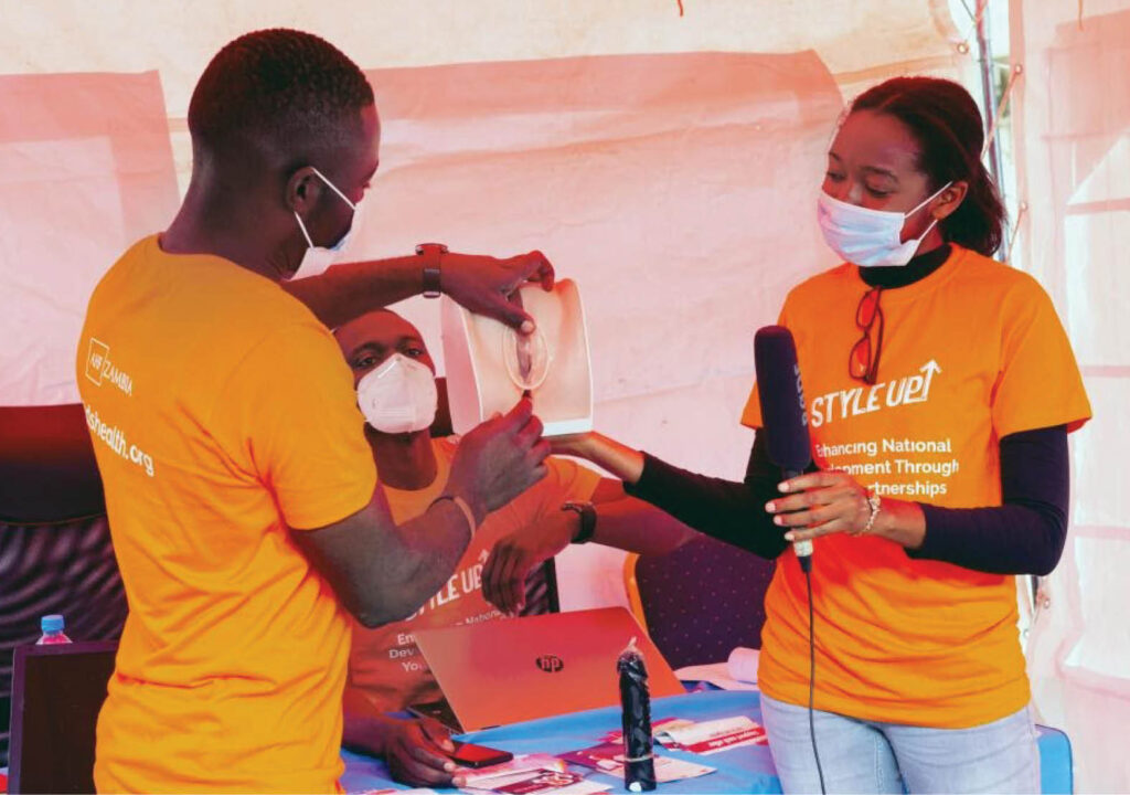 AHF_Sex Education Zambia _ Participants watch a demonstration on how to correctly use male and female condoms.