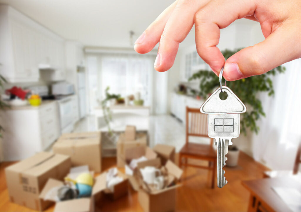 Hand with house key. Real estate and moving background.