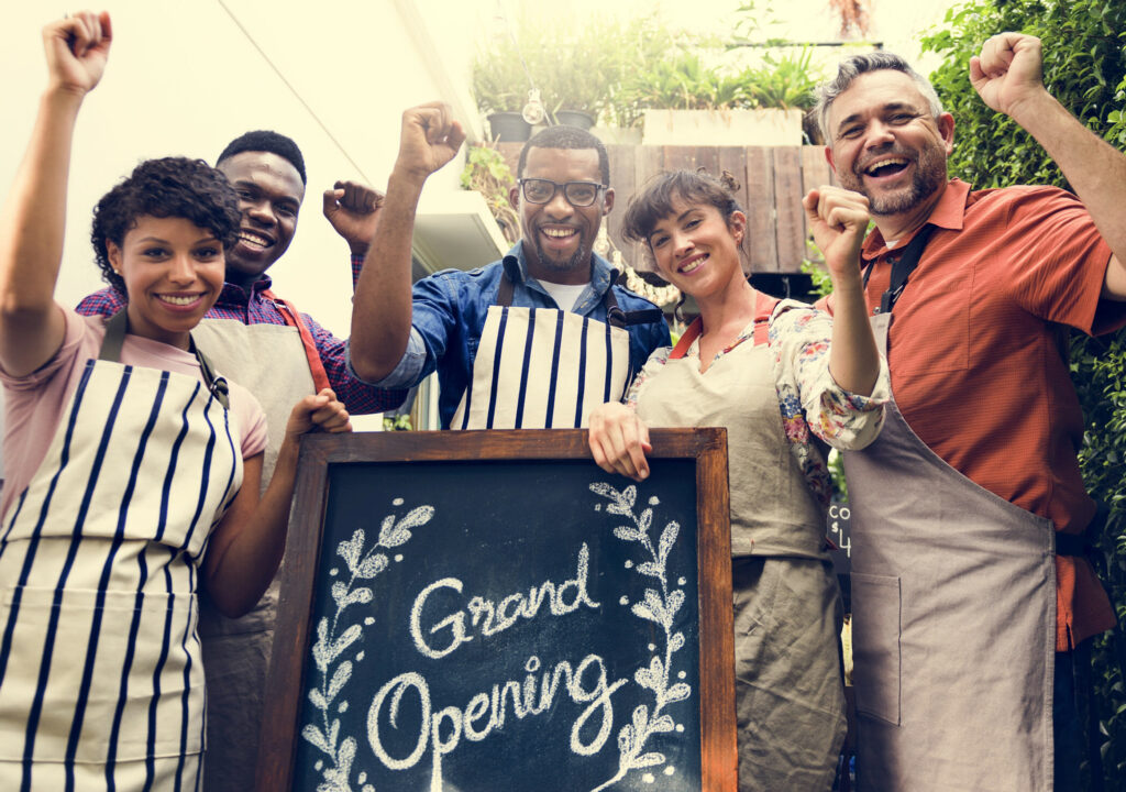 Group of friends with grand opening board together