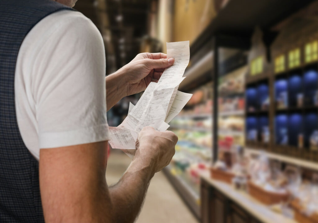 Closeup of young man holding bill to check the price in supermarket