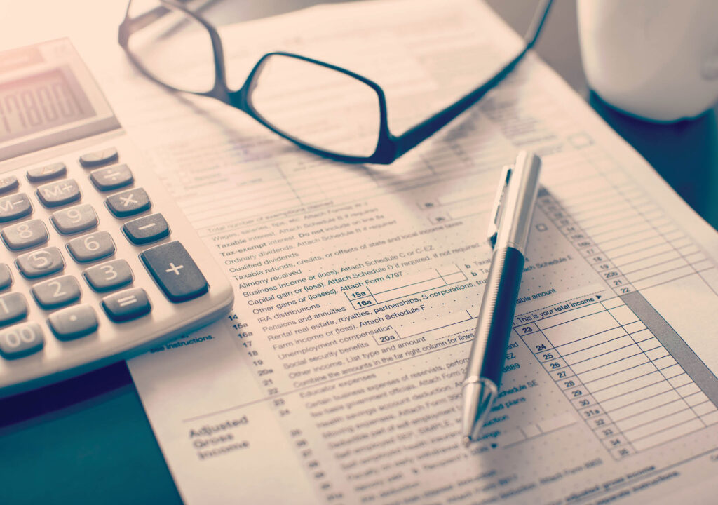 Individual income tax return form, glasses, pen and calculator on desk