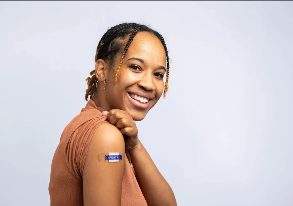 In this 2022 photo, a patient is smiling with a bandage on the injection site, where she just received an influenza vaccine. The best way to prevent seasonal flu is to get vaccinated every year. Centers for Disease Control and Prevention (CDC) recommends everyone 6-months of age and older get a flu vaccine every season.