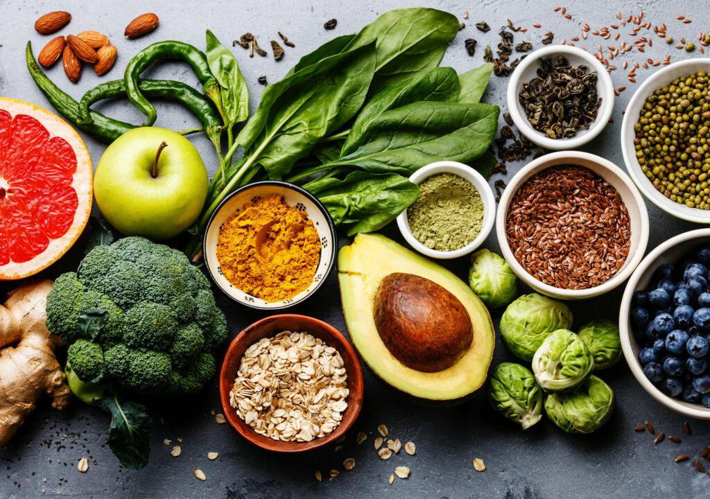 Healthy food clean eating selection: fruit, vegetable, seeds, superfood, cereal, leaf vegetable on gray concrete background
