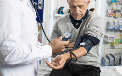 Midsection Of Male Chemist Checking Patient`s Blood Pressure. Midsection of male chemist checking blood pressure of senior patient in pharmacy