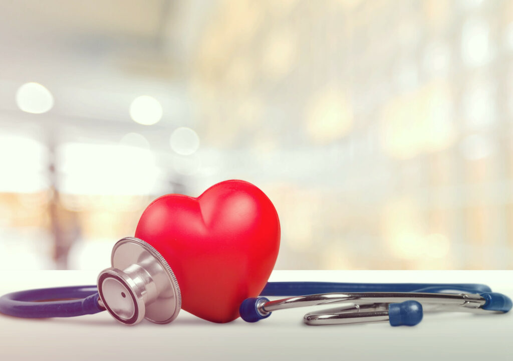 One single alone red heart love shape hand exercise ball with bandage MD medical doctor physician's stethoscope white wood background: Hospital life insurance concept: World heart health day idea