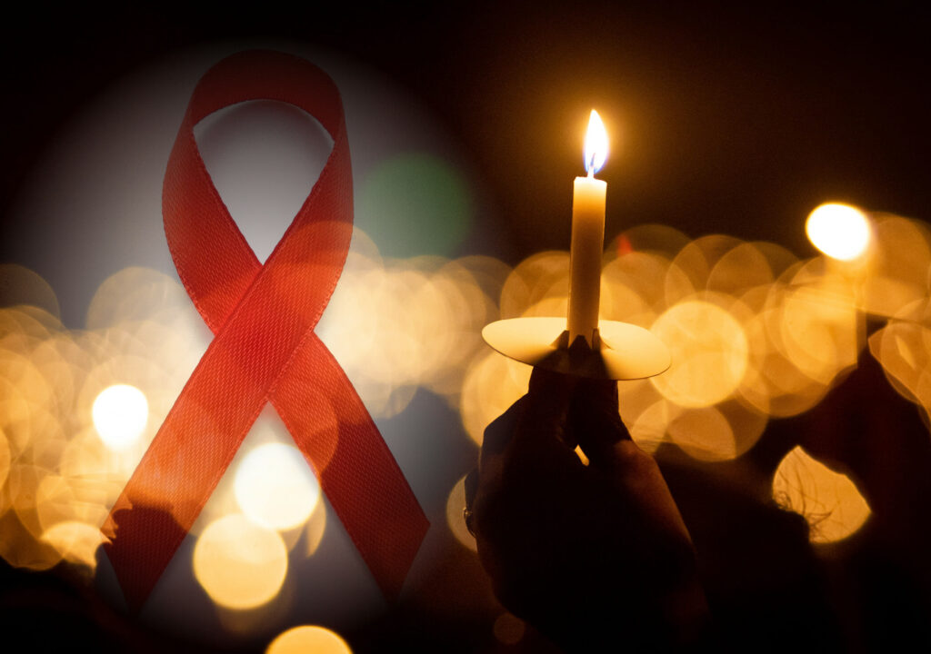 Picture of Hand holding candle on right and World AIDS day concept. Red ribbon on the right