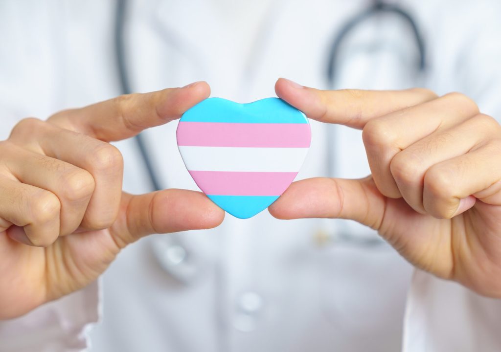 Transgender Day and LGBT pride month, LGBTQ+ or LGBTQIA+ concept. Doctor holding blue, pink and white heart shape for Lesbian, Gay, Bisexual, Transgender, and Pansexual community
