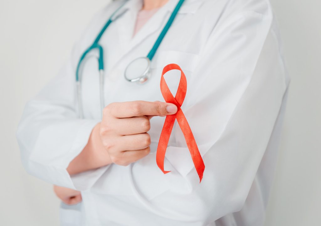 Doctor Hands is Holding Red Ribbon and Arms Crossed Posing. AIDS, HIV International Symbol of Awareness, Healthcare and Medicine Concept
