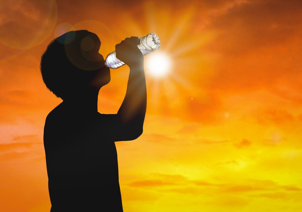 Silhouette man is drinking water bottle on hot weather background with summer season. High temperature and heat wave concept. Drink.
