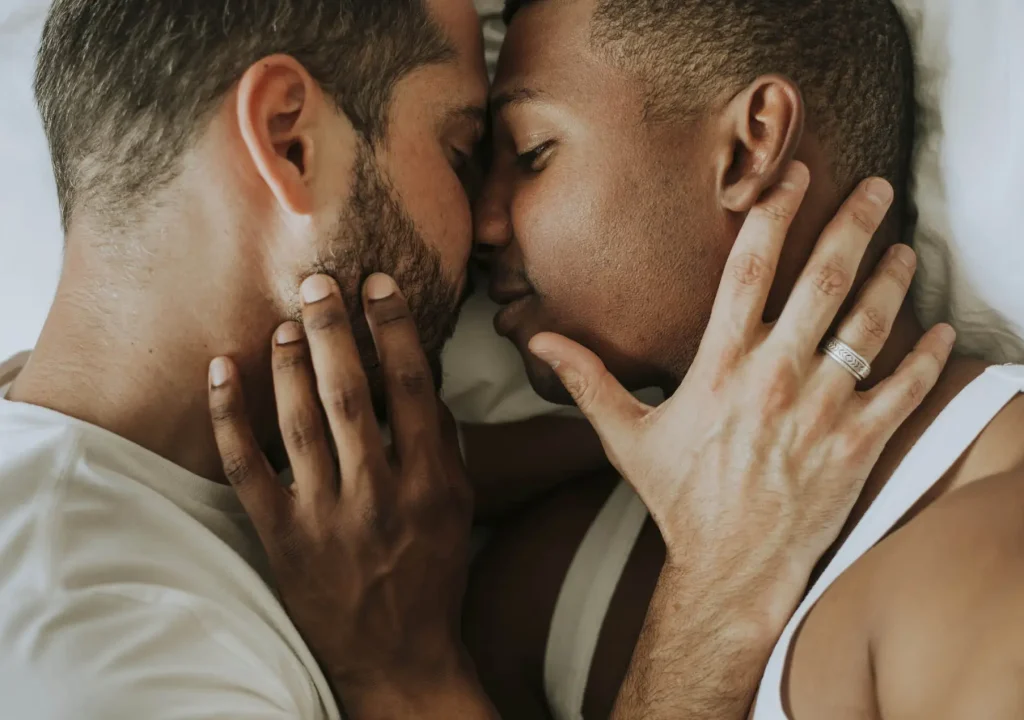Gay couple cuddling in bed