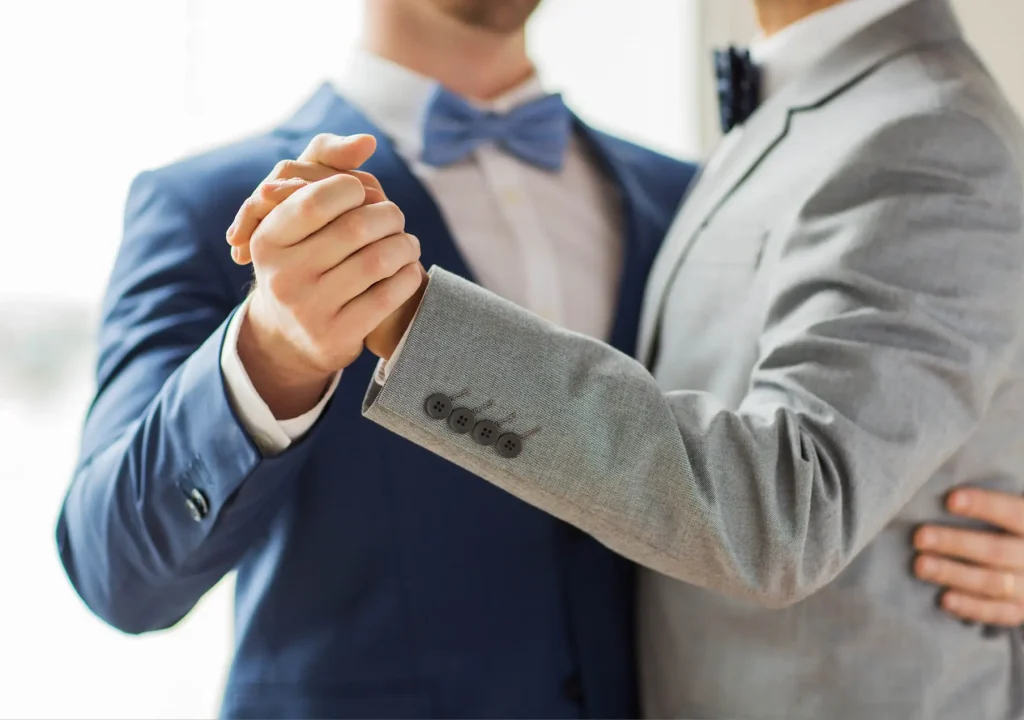 Close up of happy male gay couple dancing. People, homosexuality, same-sex marriage and love concept - close up of happy male gay couple holding hands and dancing on wedding