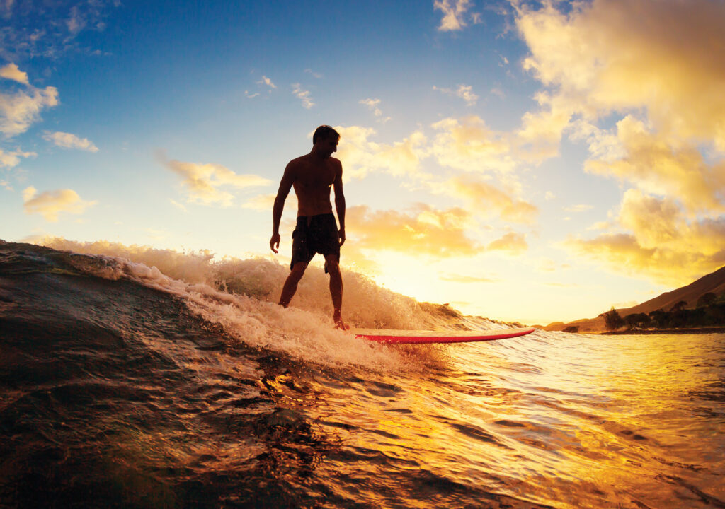 Surfing at Sunset. Young Man Riding Wave at Sunset. Outdoor Active Lifestyle.