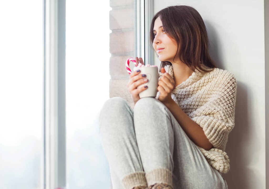 Woman siting by the window drinking coffee