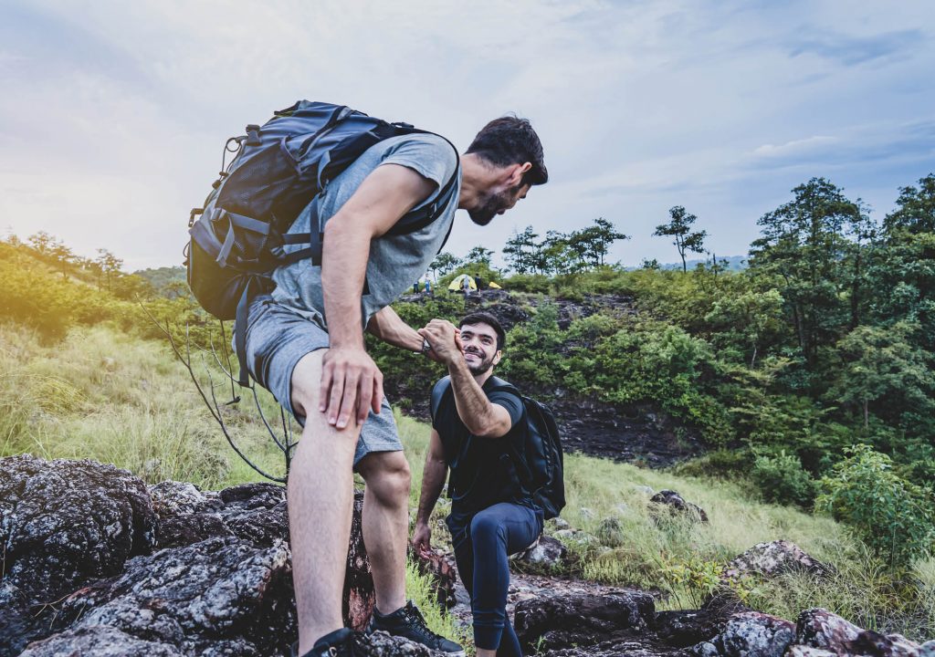 People trekking and helping each other,hikers climbing up on the mountain, Teamwork and hiking concepts