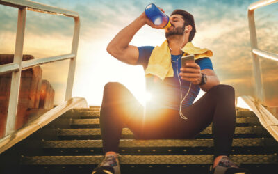 athletic man sitting on stairs and drinking water
