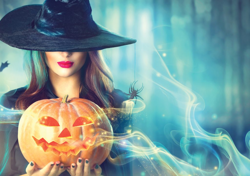 Halloween witch with a magic pumpkin in a dark forest