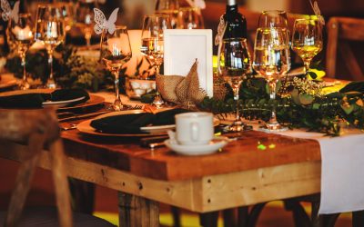 Elegant arrangement of the holiday tableware. Vintage decoration of reception dinner table. Rustic wedding table setting in fancy American restaurant. Wine glasses, plates, forks and green briefcases for the banquet