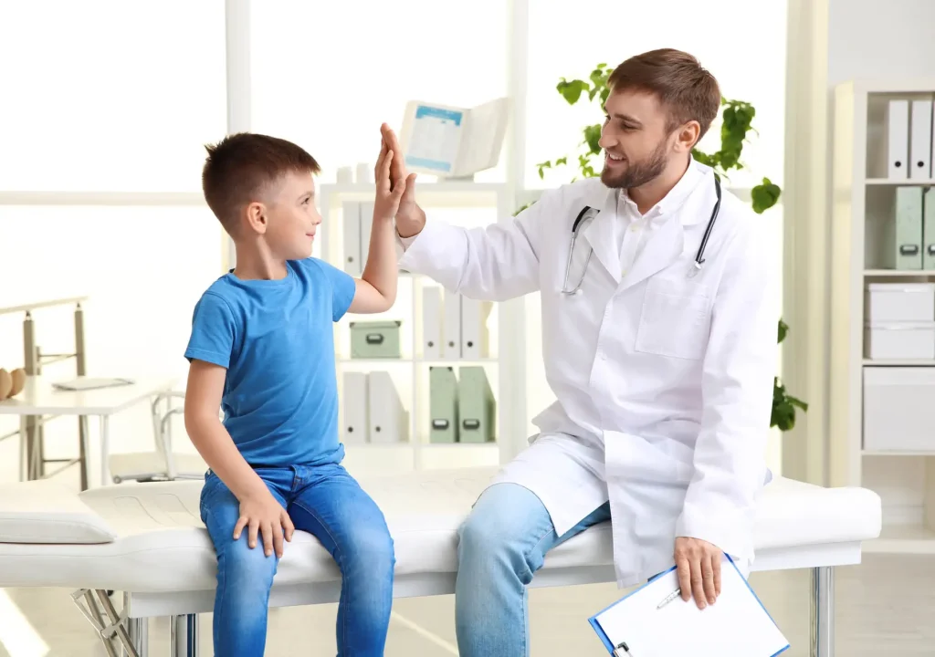 Children`s doctor giving high five to patient in hospital