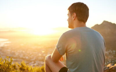 Rear view of a young guy resting on a nature trail watching the sunrise