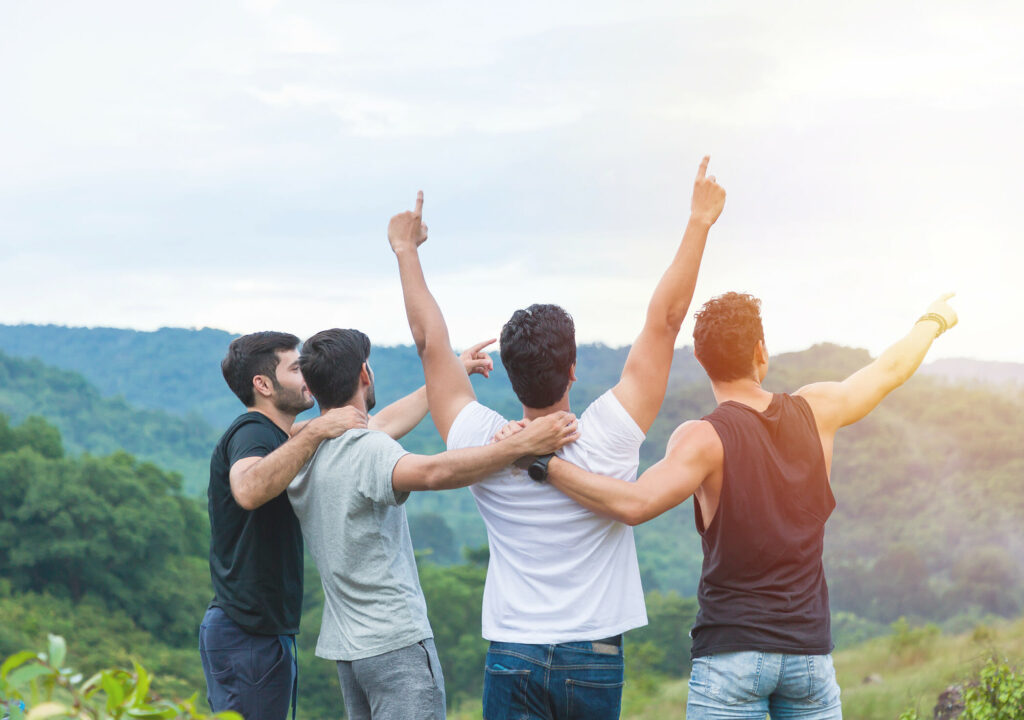 Group of male hiking and camping. Back view of group of young tourists man camping standing hugging on shoulder together and raising up his hands on mountain