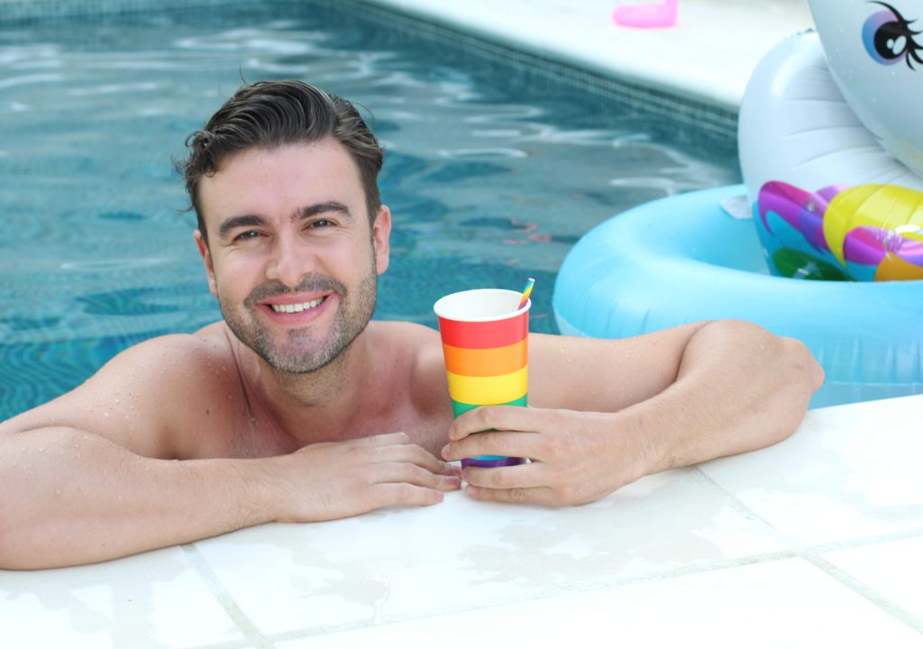Cute man drinking in rainbow cup.