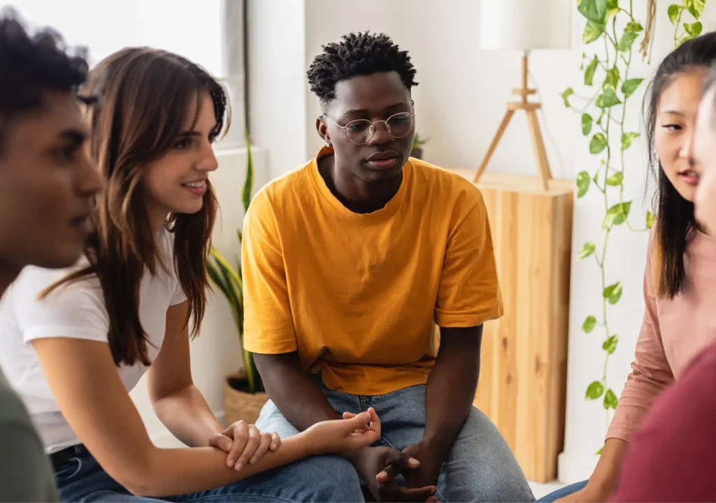 Multiracial people sitting in circle during group therapy supporting each other. Diversity, mental health and support concept. People communicating while sitting in circle and gesturing.