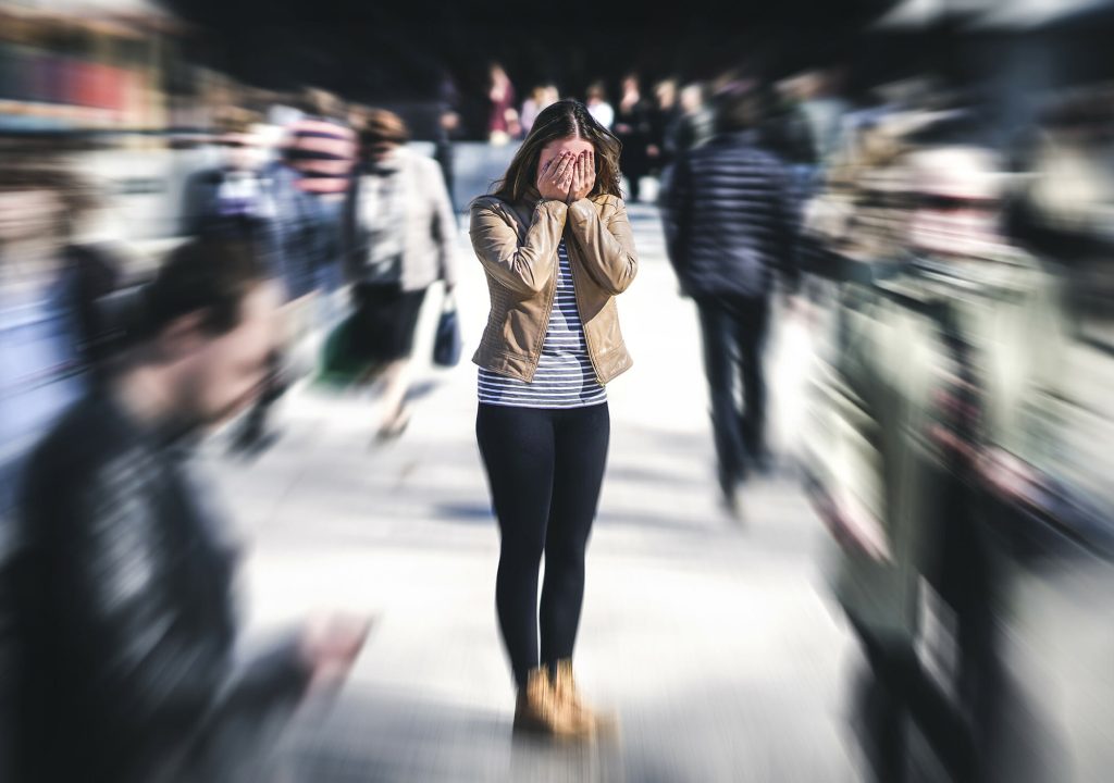 Panic attack in public place. Woman having panic disorder in city. Psychology, solitude, fear or mental health problems concept. Depressed sad person surrounded by people walking in busy street.