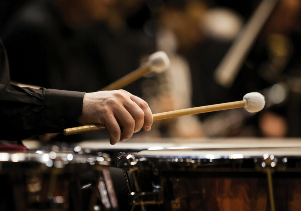 Hands musician playing the timpani in the orchestra closeup in dark colors