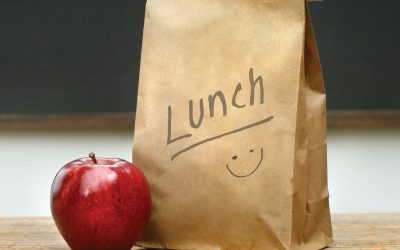 Paper lunch bag on desk with apple