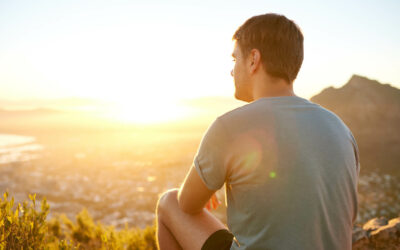 Rear view of a young guy resting on a nature trail watching the sunrise