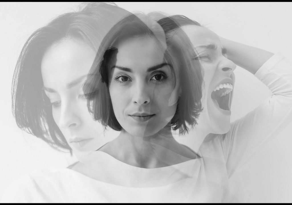 Multiple identities. Close-up photo of a young pretty brunette girl who is looking in the camera while internally suffering from a dissociative identity disorder. Double exposure.