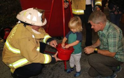 Luke Schofield (center) donates to The Salvation Army of Broward with the help of City of Fort Lauderdale Deputy Fire Chief/Fire Marshal Jeff Lucas and Robert Schofield at last year’s Christmas on Las Olas event. Photo courtesy of Goodman PR